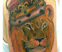 tatuaje en el brazo: cabeza de león con corona de rey