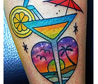 tatuaje en la pierna: copa de coctel con playa al fondo