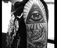 tatuaje en blanco y negro en el brazo: ojo dentro de triángulo