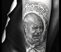tatuaje en blanco y negro en la pierna: cara de un señor con laureles