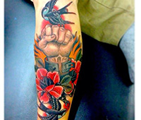 tatuaje en el brazo: un puño con flores y pájaro